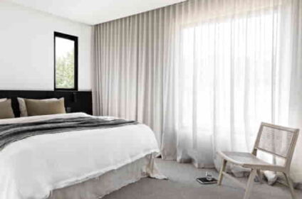 Minimalist-bedroom-with-white-bedding-black-headboard-cane-chair-and-floor-to-ceiling-linen-sheer-curtains