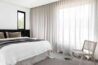Minimalist-bedroom-with-white-bedding-black-headboard-cane-chair-and-floor-to-ceiling-linen-sheer-curtains