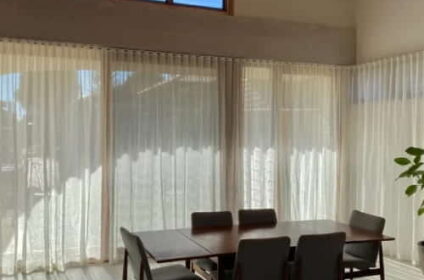 Sunlit-interior-with-seamless-sheer-curtains-Dubai-design-covering-large-windows-behind-a-six-seat-dining-table