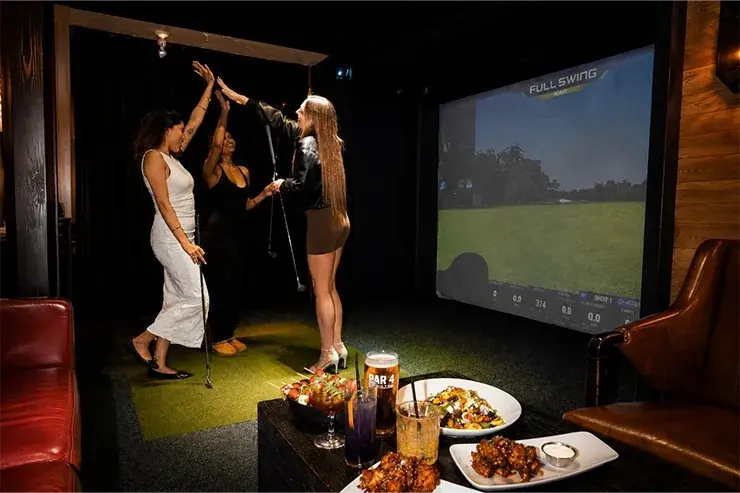 Indoor virtual golf simulator with a golfer practicing a swing in a modern entertainment space